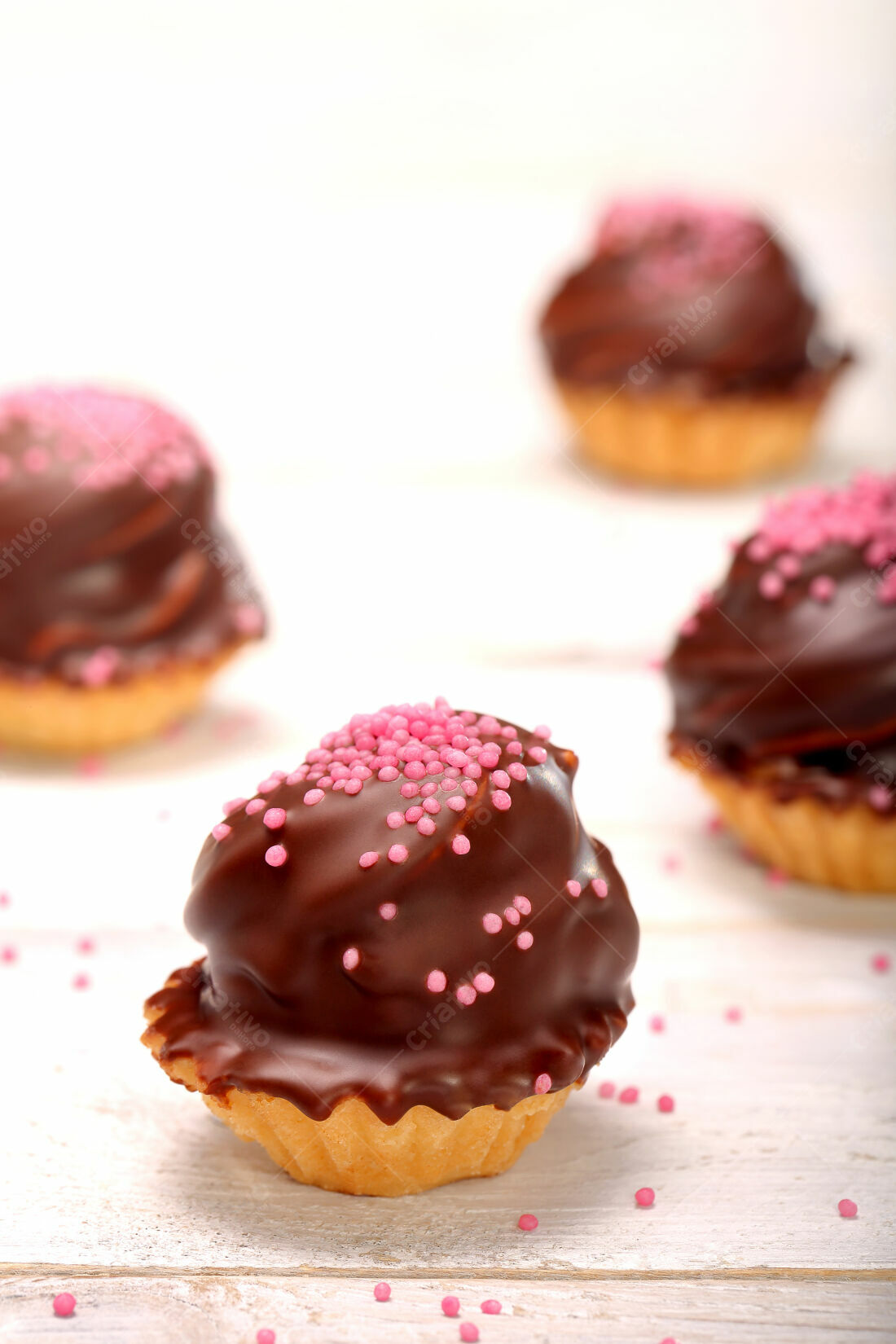 Doces cobertos com chocolate e granulado rosa